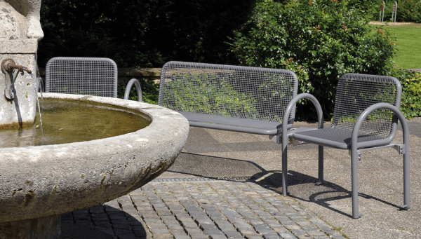 Bilde som viser Siesta Harmony benk og stoler i stål, rundt en fontene.